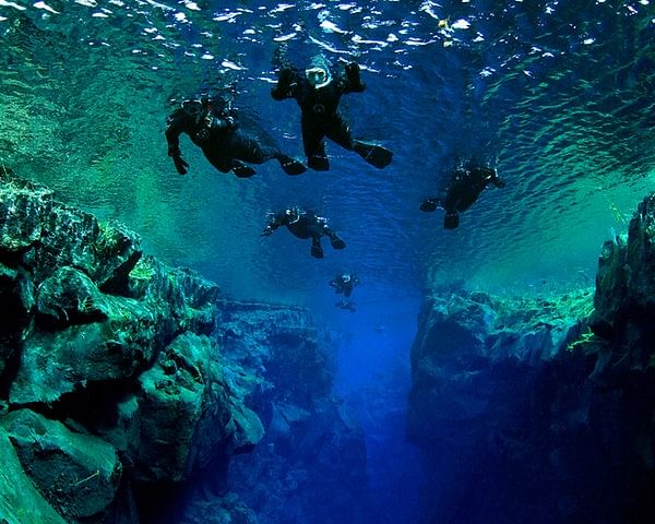 Divers explore a clear underwater crevice in Iceland's Silfra fissure between tectonic plates.