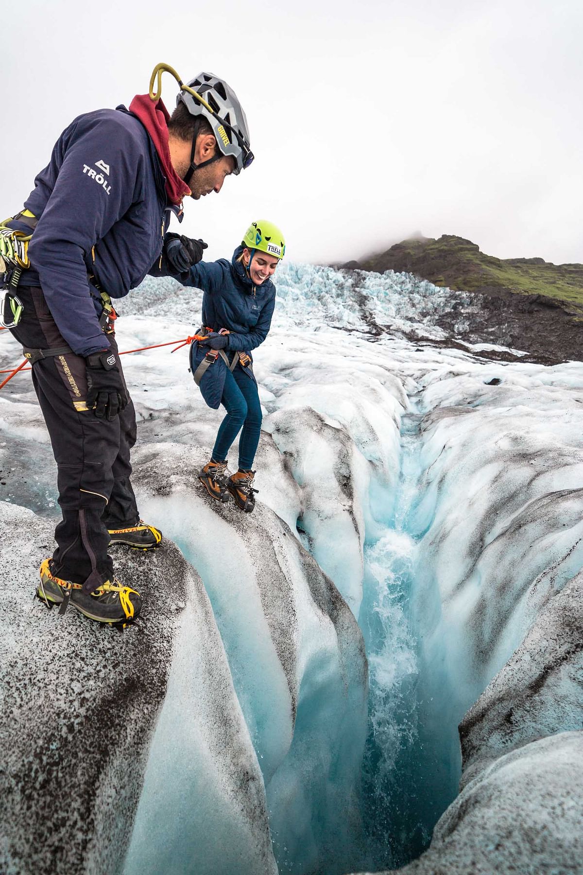 Two climbers navigating an icy crevasse on a glacier, wearing safety gear and helmets, adventure in nature.