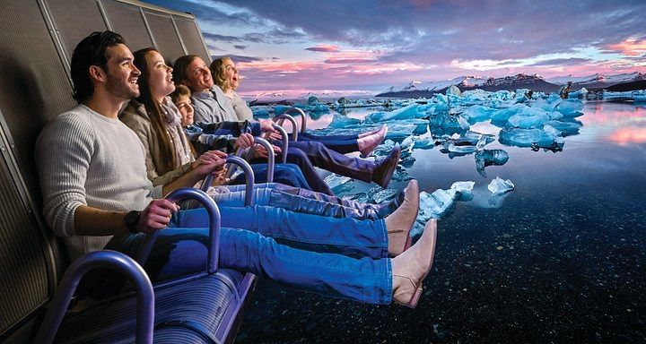 People enjoying a virtual ride experience, simulating a scenic viewing of icy landscapes and a vibrant sunset.