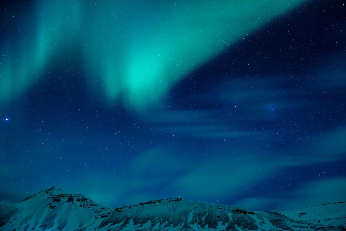 Stunning Northern Lights over snowy mountain landscape under starry sky.