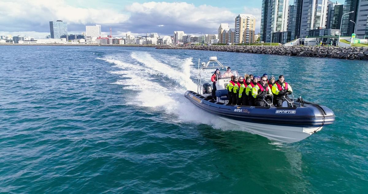 Tourists enjoying a speedboat ride in Reykjavik, with city skyline in the background.