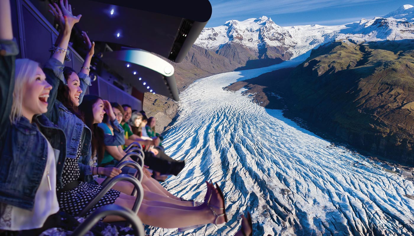 People enjoying an immersive flying theater ride over a stunning glacier landscape.