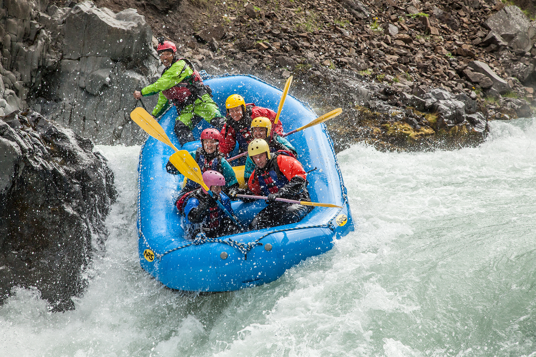 Group of adventurous rafters navigating rapids in a blue raft on a thrilling whitewater rafting trip.