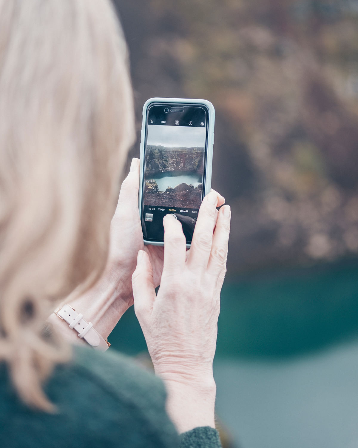 Person photographing scenic view with smartphone, capturing a landscape on a mobile screen.