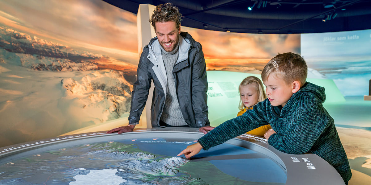 Family exploring an interactive map exhibit in a museum setting.