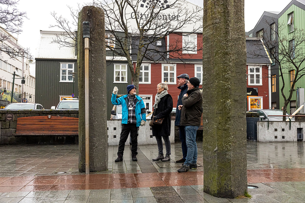Tour guide explains city landmarks to a group in a rainy urban square.