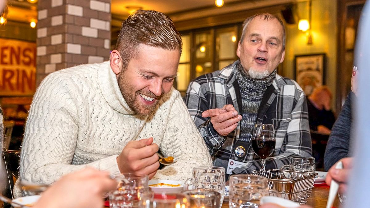 Two men enjoying conversation and drinks at a cozy restaurant, with warm lighting and a friendly atmosphere.
