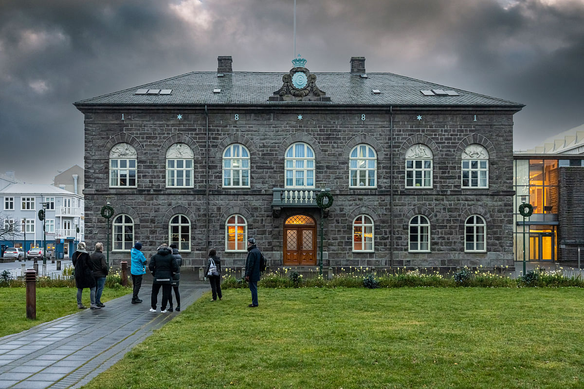 Historic stone building in Reykjavik, Iceland, with people gathered outside on a cloudy day.