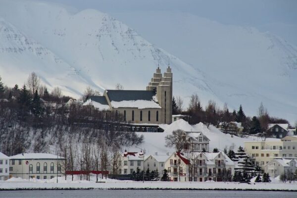 Scenic view of a snowy village with a prominent church and mountain backdrop.