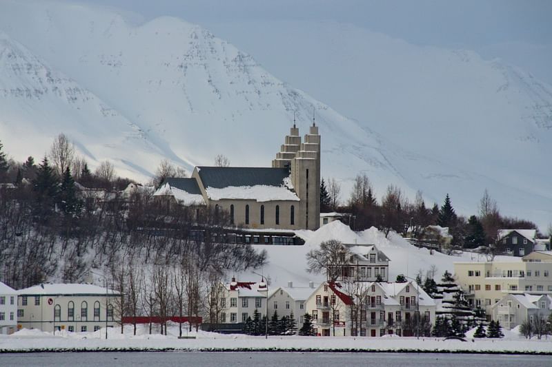 Scenic view of a snowy village with a prominent church and mountain backdrop.