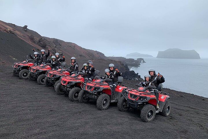 Group enjoying ATV adventure on volcanic landscape by the sea on a cloudy day.