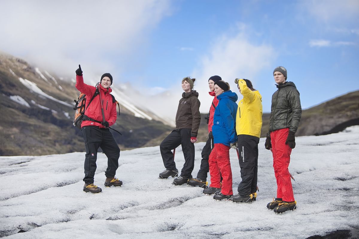 Group of hikers with gear exploring a snowy mountain landscape under a blue sky.