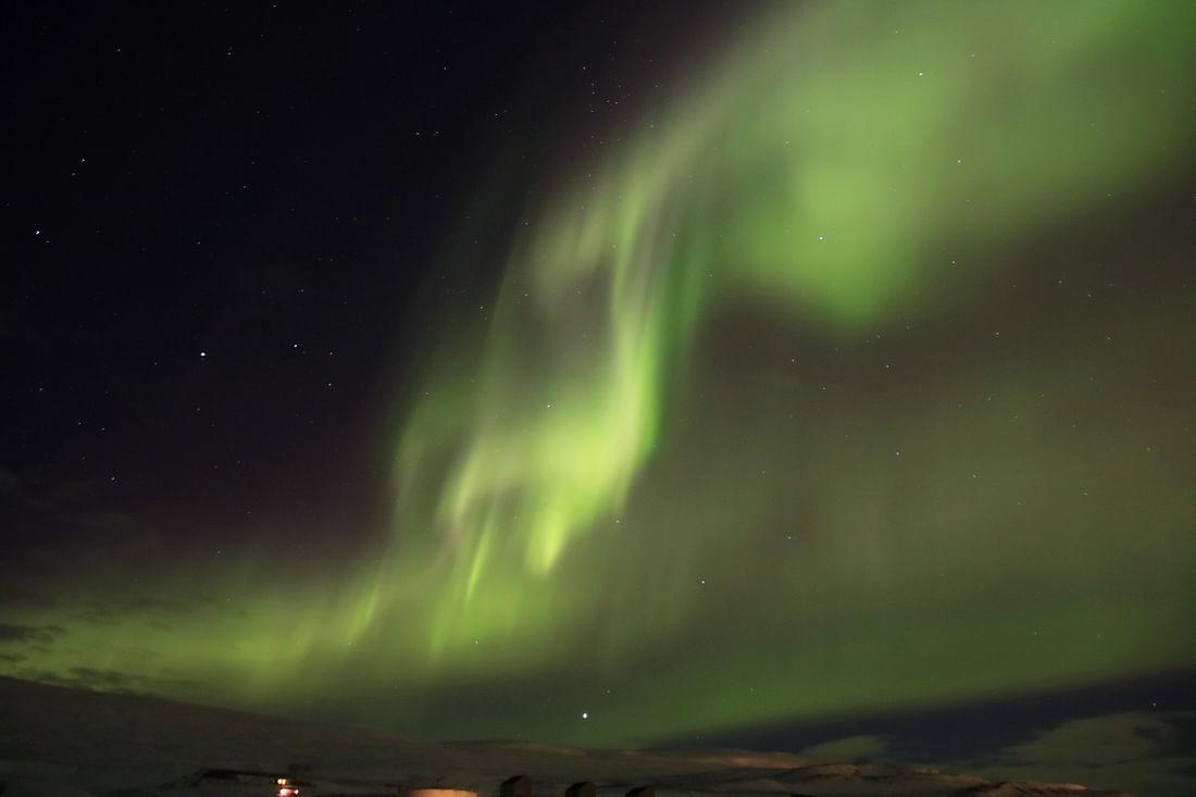 Northern lights illuminate night sky with vibrant green aurora, creating a stunning natural display.