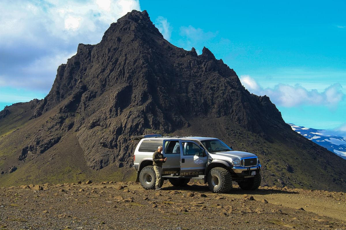 Off-road vehicle in rugged mountainous terrain under clear blue sky.