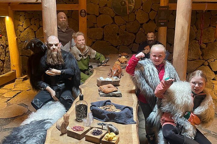 Kids in Viking costumes pose with mannequins in a rustic hall, showcasing historic Viking culture and lifestyle.