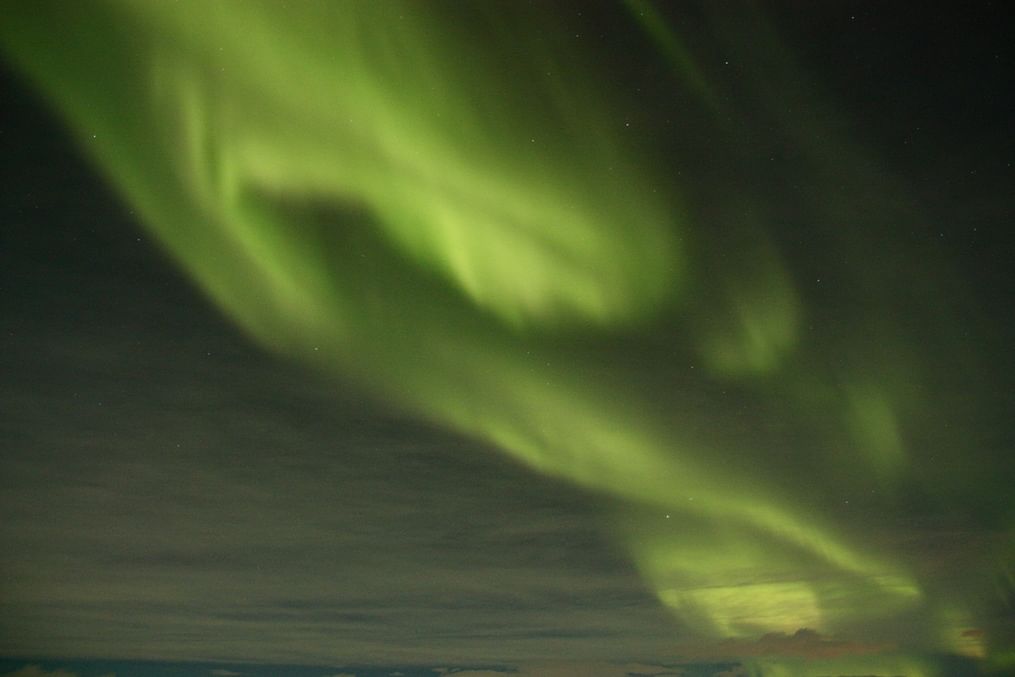 Vivid green aurora borealis dancing in the night sky, showcasing nature's mesmerizing light display.