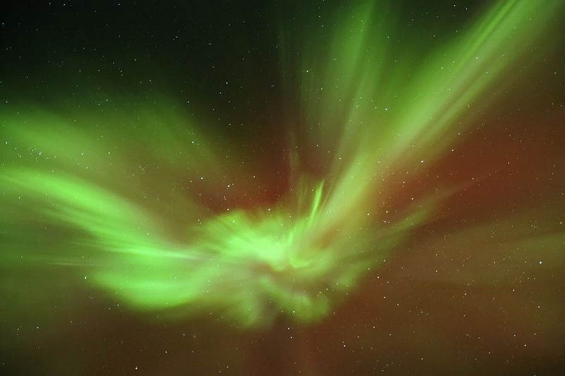 Vibrant green aurora borealis illuminating the night sky with stars in the background.