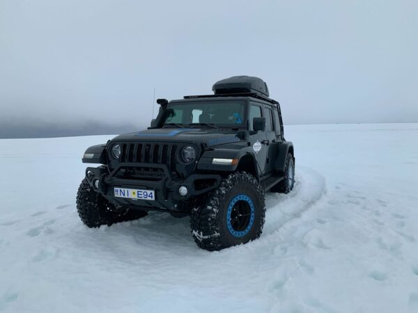 Off-road vehicle navigating snowy terrain under an overcast sky.